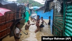 Rohingya refugee children play in flood waters at the Rohingya refugee camp in Kutupalong, Bangladesh, Wednesday, July 28, 2021. (AP Photo/ Shafiqur Rahman)