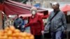 Italy, Catania, A woman wearing a protective face mask looks on at a market as vendors 