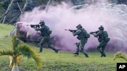 Soldiers from Taiwan's special forces move past colored smoke during a helicopter landing training and all-out defense demonstration in Taipei, Taiwan, Dec. 14, 2017. 