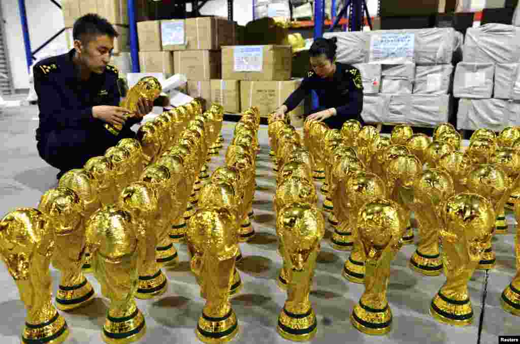 Customs officers look at confiscated counterfeit FIFA World Cup replica trophies in Yiwu, Zhejiang province, China, April 16, 2014. The local customs office seized a total of 1,020 unauthorized FIFA World Cup replica trophies before they were shipped out to Libya.