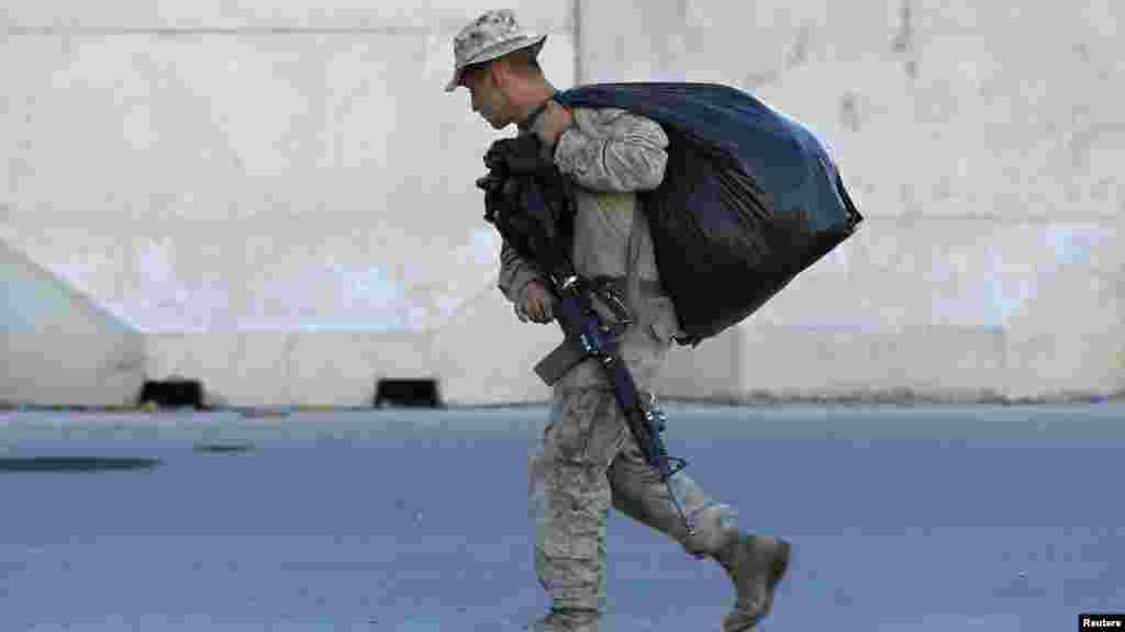 Seorang marinir AS membawa barang-barangnya di Camp Bastion di provinsi Helmand (25/10). (Reuters/Omar Sobhani) 