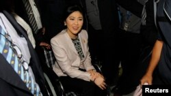 Thai Prime Minister Yingluck Shinawatra is helped in a wheelchair as she arrives at the National Anti-Corruption Commission office in Nonthaburi province, on the outskirts of Bangkok, March 31, 2014.