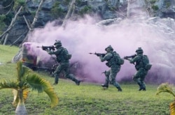 FILE - Soldiers from Taiwan's special forces move past colored smoke during a helicopter landing training and all-out defense demonstration in Taipei, Taiwan, Dec. 14, 2017.