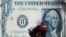 FILE - An Egyptian vendor adjusts her veil in front of a giant poster of a US dollar outside an exchange office in Cairo, Egypt, March 28, 2011.