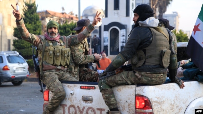 Syrians rebel fighters celebrate near the Clock Tower in the central city of Homs on Dec. 8, 2024, after rebel forces entered Syria's third city overnight.