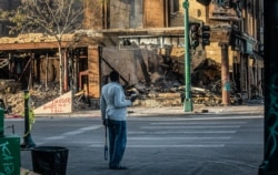 A man looks at the destruction aftermath of businesses along Lake Street, May 31, 2020, in Minneapolis.