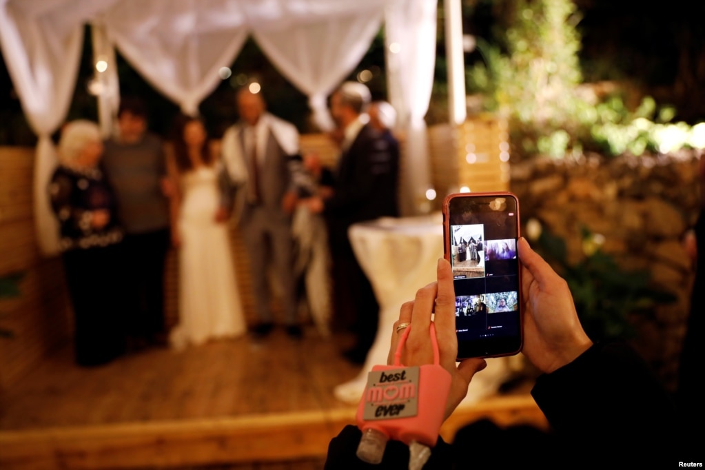 Una mujer trasmite por videoconferencia con amigos y familiares la ceremonia de boda de una pareja israelí en Ein Hemed Forest, un sitio que ofrece bodas gratis a pequeña escala a parejas que no puedan celebrar sus bodas debido a las restricciones impuestas para frenar la pandemia.&nbsp;