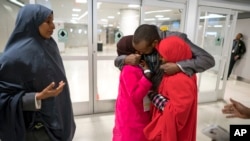 FILE - Ismail Issack, father of Miski Shalle, 11, and Muzamil Shalle, 14, embraces his children as their mother Halima Mohamed, far left, looks on as they reunite for the first time in seven years at John F. Kennedy International Airport in New York.