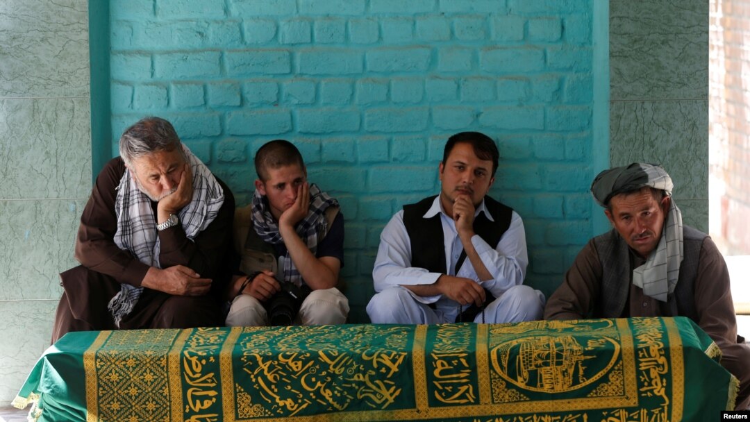 Para pelayat duduk di samping peti jenazah wartawan Afghanistan, Zabihullah Tamanna sebelum upacara pemakaman di Kabul, Afghanistan, 7 Juni 2016. 