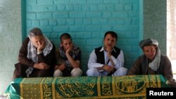 Para pelayat duduk di samping peti jenazah wartawan Afghanistan, Zabihullah Tamanna sebelum upacara pemakaman di Kabul, Afghanistan, 7 Juni 2016. 