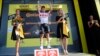 L'Australien Caleb Ewan célèbrant sa victoire sur le podium, flanqué de deux hôtesses, après la seizième étape du Tour de France à Nîmes, le 23 juillet 2019. La pratique sexiste des "miss" sur le podium a finalement été modifiée en août 2020. (AP/Christophe Ena).