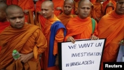 Buddhist monks hold a placard as they protest in front of the U.N. office in Bangkok, October 3, 2012. 