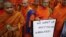 Buddhist monks hold a placard as they protest in front of the U.N. office in Bangkok, October 3, 2012. 