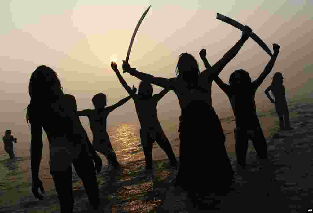 Indian Hindu holy men, or Sadhus, are silhouetted as they celebrate in the water at Sangam, the confluence of the rivers Ganges, Yamuna and mythical Saraswati, during the royal bath on Makar Sankranti at the start of the Maha Kumbh Mela in Allahabad.