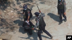 افسران پلیس ضدشورش میانمار در حال متفرق‌کردن تظاهرکنندگان در شهر تارکاتا در حومه یانگون، یک معترض را بازداشت کرده‌اند. (١٦ اسفند ١٣٩٩)
