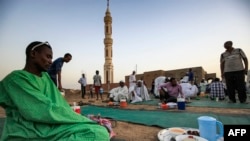 Pria Sudan berkumpul setelah salat maghrib di pinggir jalan di ibu kota Khartoum, setelah berbuka puasa Ramadan, 25 April 2020, di tengah pandemi COVID-19. (Foto: ASHRAF SHAZLY / AFP)
