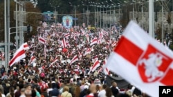 FILE - Protesters with old Belarusian national flags march at an opposition rally in Minsk, Belarus, on Sept. 6, 2020.