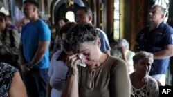 Orthodox faithful attend a memorial service for the victims of a forest fire, inside a church at Mati village, east of Athens, July 29, 2018.