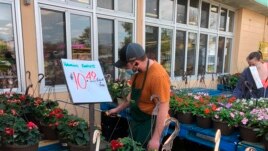 A worker wearing a mask to protect against the coronavirus waters plants at a Joe Randazzo’s store in Roseville, Mich., Saturday, May 2, 2020.
