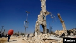 A picture of Syria's President Bashar al-Assad is displayed on a damaged structure at the entrance of al-Dukhaneya neighborhood near Damascus, October 7, 2014