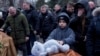 A boy puts a toy on a coffin during a Feb. 5 funeral service in Poltava, Ukraine, for Dmytro Yavorskyi, 37; Sofia Yavorska, 9, and Olena Yavorska 38, who were killed on Feb. 1 by a Russian strike.