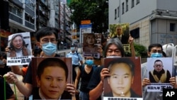 FILE - Pro-democracy demonstrators hold up portraits of jailed Chinese civil rights activists, lawyers and legal activists as they march to the Chinese liaison office in Hong Kong, June 25, 2020. They demand to abolish the national security law. 