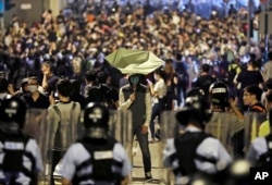A protester holds a yellow umbrella in front of police officers after clashing as thousands of people march in a Hong Kong street, Nov. 6, 2016.