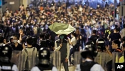 A protester holds a yellow umbrella in front of police officers after clashing as thousands of people march in a Hong Kong street, Nov. 6, 2016.