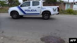 A police patrol car is seen near a bloodstain on a street in Duran, Ecuador, on October 13, 2024. Seven people were shot dead October 12 in the third massacre this week in the troubled town of Duran.