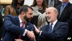 Pennsylvania Gov. Tom Wolf, right, shakes hands with Rep. Mark Rozzi, D-Berks, after signing legislation into law at Muhlenberg High School in Reading, Pa., Tuesday, Nov. 26, 2019.