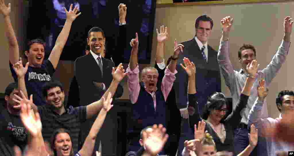 Students and professors cheer while dancing with cutouts of President Barack Obama, left, and Republican presidential candidate Mitt Romney, right, prior to watching the third televised presidential debate at Harvard University's John F. Kennedy School of