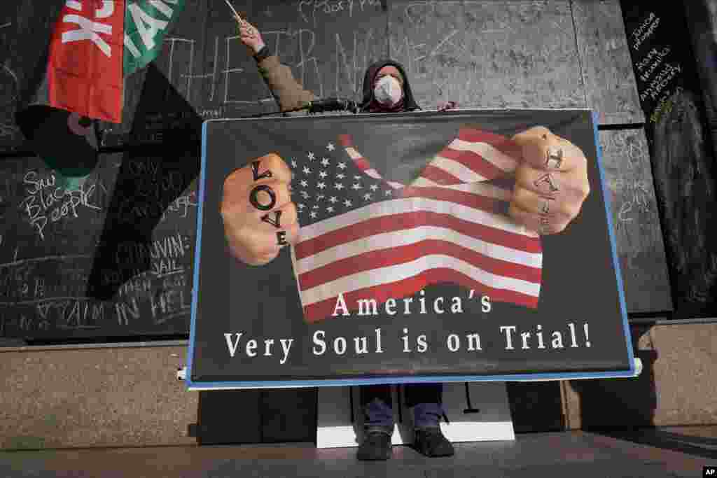 A protester holds a sign across the street from the Hennepin County Government Center in Minneapolis where testimony continues in the trial of former Minneapolis police officer Derek Chauvin.