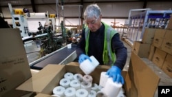 Scott Mitchell fills a box with toilet paper at the Tissue Plus factory, Wednesday, March 18, 2020, in Bangor, Maine. The new company has been unexpectedly busy because of the shortage of toilet paper brought on by hoarders concerned about the coronavirus