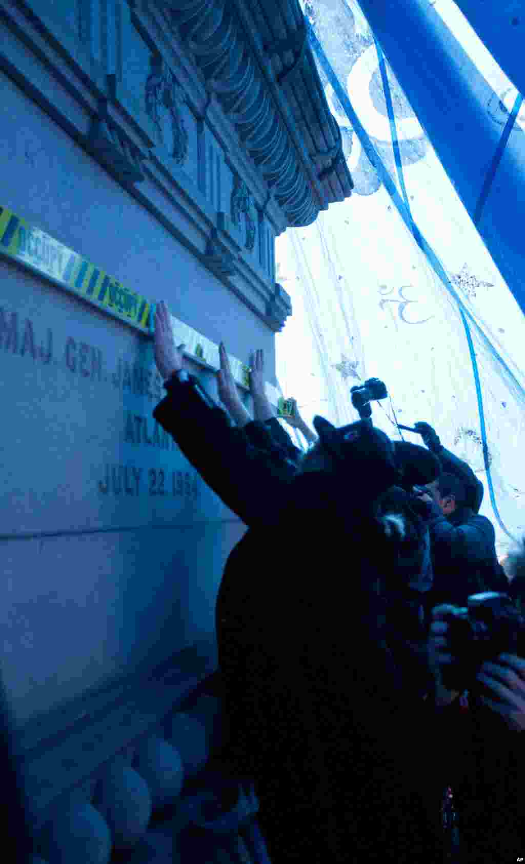 Demonstrators apply occupy-themed caution tape to the statue underneath the symbolic "tent" they built in McPherson Square. (Alison Klein/VOA)