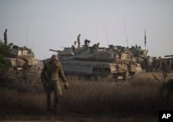 Israeli soldiers work on their tanks at a staging area near the Israel-Gaza Border, Wednesday, July 9, 2014.