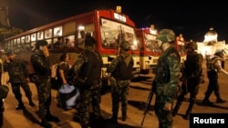 FILE - Thai soldiers stand as anti-government protesters board a bus to head home, at the Royal Plaza in Bangkok.