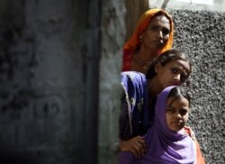 Seorang wanita dan dua gadis mengintip dari ambang pintu di lingkungan Hindu di Lyari, di Karachi, Pakistan, Selasa, 5 Mei 2009. (Foto: AP)