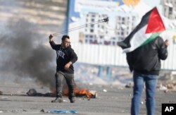 Palestinian demonstrator throws stones during clashes with Israeli troops following protests against U.S. President Donald Trump's decision to recognize Jerusalem as the capital of Israel, in the West Bank city of Ramallah, Feb 2, 2018.