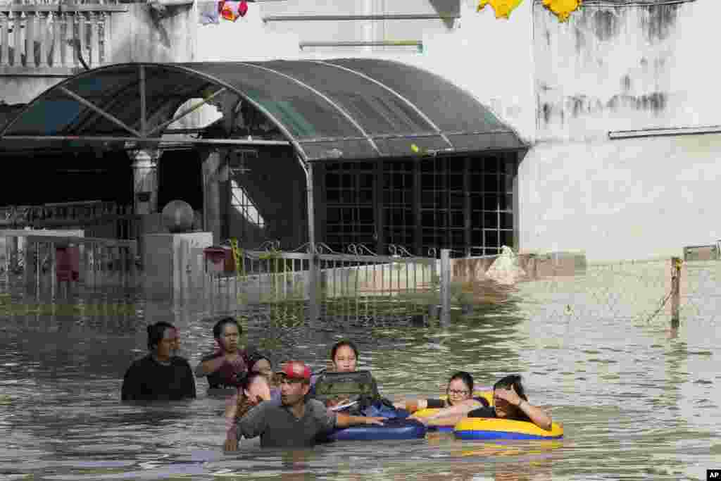 Warga berusaha mengarungi jalan yang terendam banjir setelah hujan lebat mengguyur Shah Alam, pinggiran Kuala Lumpur, Malaysia, Senin, 20 Desember 2021. (Foto: AP)