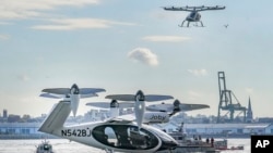 This file images shows an electric vertical takeoff and landing (eVTOL) aircraft, flying above the Joby eVTOL aircraft, during a demonstration of eVTOLs Nov. 13, 2023, in New York. (AP Photo/Bebeto Matthews, File)