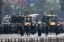 Police advance with heavy construction equipment towards protesters demonstrating against the military coup in Yangon, Myanmar, Feb.22, 2021.