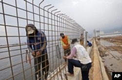 FILE - Workers build a wall that will be used as a barrier to prevent sea water from flowing onto land and cause flooding in Jakarta, Indonesia, Dec. 8, 2015.