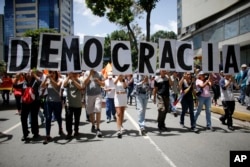 FILE - Anti-government demonstrators hold a poster that reads in Spanish "Democracy" during a protest against Venezuela's President Nicolas Maduro in Caracas, Venezuela, Aug. 12, 2017.