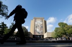 Penggemar foto berkumpul di Perpustakaan Hesburgh dengan mural Word of Life, juga dikenal sebagai Touchdown Jesus, di Universitas Notre Dame. (Foto: AP/Darron Cummings)