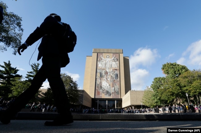 Penggemar foto berkumpul di Perpustakaan Hesburgh dengan mural Word of Life, juga dikenal sebagai Touchdown Jesus, di Universitas Notre Dame. (Foto: AP/Darron Cummings)