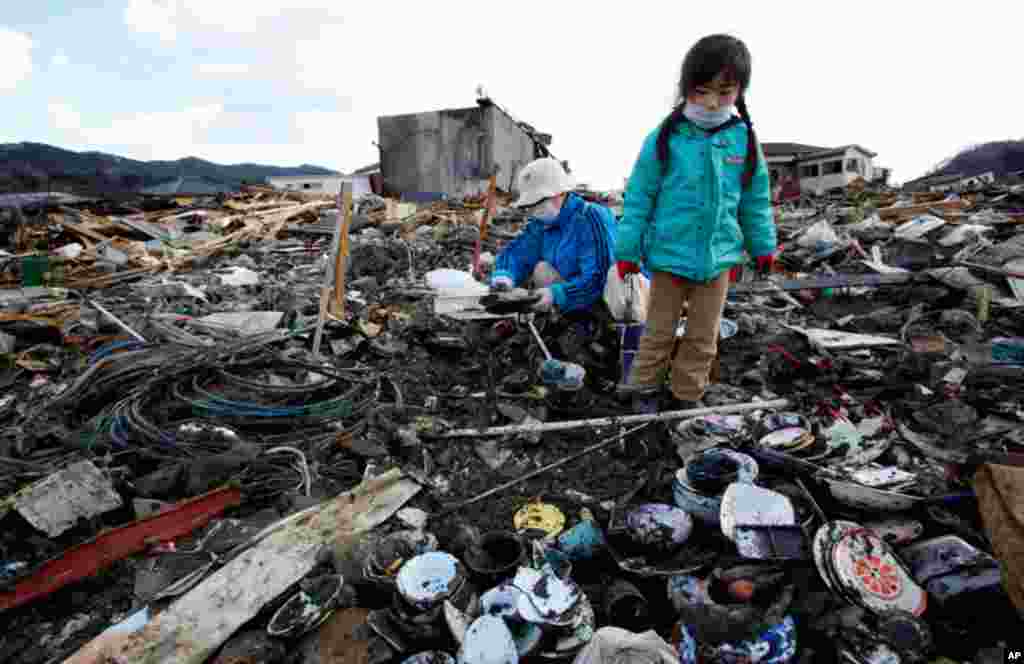March 23: Tokiko Takada and her granddaughter Mai search through the rubble of their home destroyed by the March 11 tsunami at Kesennuma, northern Japan. (AP Photo/Shizuo Kambayashi)
