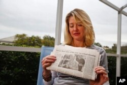 In this Jan. 30, 2019, photo, Mechelle Boyle holds a newspaper with a photo from the school shooting showing her embracing Cathi Rush. (AP Photo/Brynn Anderson)