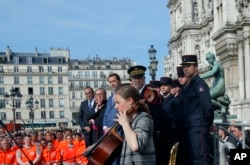 French Interior Minister Christophe Castaner, third left, and other officials listen to cello player Armance Quero during a ceremony in front of the Paris city hall, April 18, 2019.