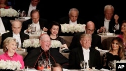 Cardinal Timothy Dolan sits between rival presidential candidates Hillary Clinton, left, and Donald Trump, who’s accompanied by wife Melania Trump, at a Catholic charity dinner in New York, Oct. 20, 2016.
