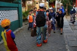 Hendrawan and his son are greeted by children as they arrive to teach. (REUTERS/Willy Kurniawan)